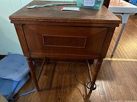 Wooden cabinet stand housing Kenmore sewing machine, showing side and drawer details.