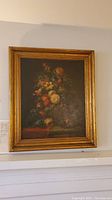 Framed flower painting hanging on a wall, includes paperwork below the painting