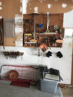 Wide view of tools hanging on racks, red grocery cart on floor, AM/FM radio, and storage bin with miscellaneous items