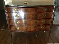 Full front view showing serpentine drawers, brass handles and glass top