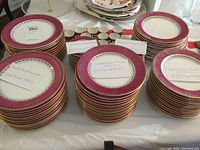 Overview of stacked plates, bowls, cups and saucers with handwritten labels.