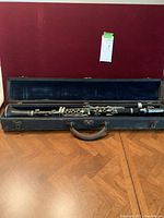 Vintage wooden clarinet in open case on wooden floor, showing full length inside the velvet-lined hard case.