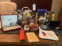 Overall view of Nestle collectible items arrayed on a flat surface showing spoons, bags, clocks, watch, tin box and other Nesquik and Stouffers branded items