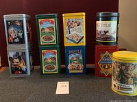 Overview of all nine Nestle collector tins arranged in three rows. Various vintage and modern designs visible.