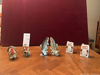 Wide view of three sets of salt and pepper shakers on wooden table against red background.