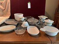 Overview of various dishes including Corning Ware, glass bowls, milk glass pieces with a lace edge milk glass dish that has a hairline crack, and other assorted glass and ceramic dishes.