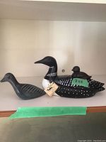 Front view of ceramic loon with tag showing JP Crafts brand, alongside soapstone bird figure