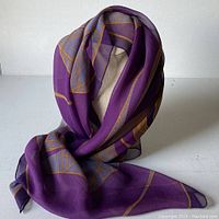Silk chiffon scarf draped to show color and fabric texture. Dominant purple with golden and blue design.