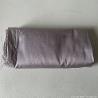 Folded piece of violet thistle colored fabric showing neat edges and slight fraying at one end.