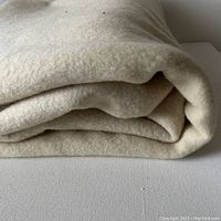 Folded cream wool blanket showing fabric texture and thickness.