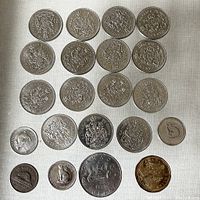 Photo showing a mixture of multiple Canadian half dollars arranged with other valued coins on a light surface.