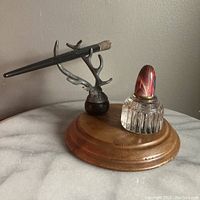 Overall view showing the cast metal antler pen holder, wooden base, glass inkwell with brass cap, and black pen resting in antlers.