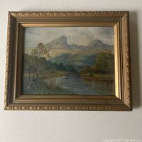Full front view of the framed oil painting showing a lake scene with hills and a small boat.