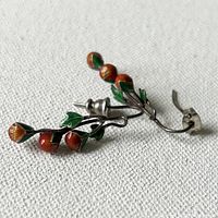 Close-up side view of sterling silver Art Nouveau style guilloche enamel strawberry earrings showing intricate enamel detail on strawberries and green leaves with silver vine design.