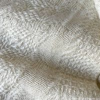 Close-up showing the detailed woven texture of the wool throw blanket in cream color.