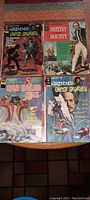 Four vintage comic books including two Grimm's Ghost Stories, one Spine-Tingling Tales, and one Milky Bounty laid on a table