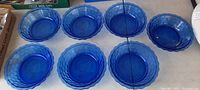 Seven deep blue glass plates arranged in two rows, showing the honeycomb textured rims and the solid color.