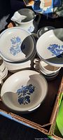 Box of assorted Pfaltzgraff vintage dishware with blue floral pattern including pitchers, bowls, plates, and cups.