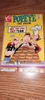 Front cover of vintage Popeye the Sailor comic book showing Popeye and characters with stack of pancakes and 'all you can eat $1.00' sign