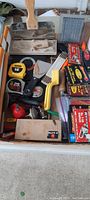 Photo showing various shop tools including tape measures, brushes, staplers, putty knife, and small boxes of staples and fasteners.