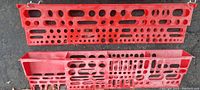 Photo of two red plastic wall-mounted tool holders with various sized round and rectangular holes for tool storage, showing their length and mounting hooks.