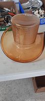 Top view of vintage amber top hat shaped heavy glass art piece showing ribbed texture on crown and smooth brim.