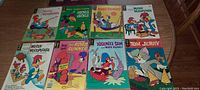 Full view of all 8 vintage comic books arranged on a table showing titles and cover art including Woody Woodpecker, Bugs Bunny, Heckle & Jeckle, Road Runner, Yosemite Sam, and Tom Jerry.