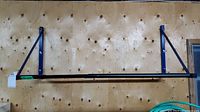 Front view of the full tire rack mounted on wooden wall, showing horizontal bar and support brackets.