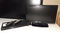 Front view of 19-inch RCA TV and Sony Blu-ray player with remotes on table