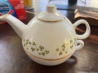 Photo showing white bone china teapot with shamrock pattern and gold trim on handle, lid, spout, and base