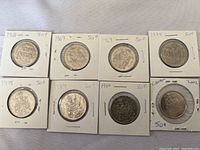 Photo showing all 8 Canadian half dollar coins in labeled cardboard holders with visible dates and denomination markings.
