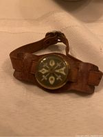 Front view of the Cub Scout leather wrist compass showing the dial of the compass embedded in the brown leather strap.