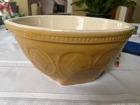 Side view showing light brown exterior with embossed geometric patterns around the bowl and cream-colored interior rim.