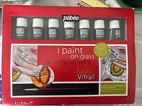 Front view of boxed Pebeo Vitrail glass paint set showing seven small bottles in the box with red packaging and branding.