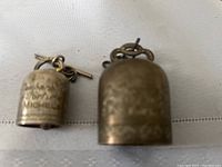 Photo showing both bells with visible inscriptions and metal loop handles.