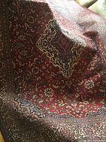 Photo showing the center section of the rug with red field and cream-colored medallion pattern surrounded by floral motifs.
