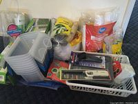 Wide photo showing all items in the lot including plastic containers, food storage rolls, disposable cups and plates.