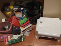 Overview photo showing all household items including step stool, cleaning cloths, bins, cleaning products, sanitizer, hot water bottle, teeth health care products, air purifier/sterilizer