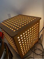 Side view of wooden slat side table illuminated internally, showing the lattice pattern.