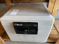 Front view of Sentry safe showing grey textured body and black locking mechanism with key in lock.