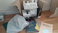 Overhead view of Brother Lock 1134D serger in cardboard box showing machine, accessories, manual and dust cover