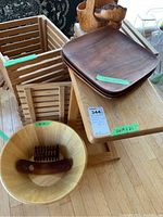 Photo showing wooden side stand, wood slat crates stacked, hand turned wooden bowls, large wooden plates and wooden salad bowl with salad utensils.