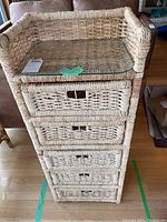 Front view of the 5-drawer wicker storage unit showing the glass top and woven drawer fronts.