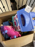 Top view showing pink airplane toy, blue roof of Fisher Price house, and various figurines inside a cardboard box.