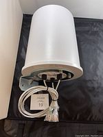 White cylindrical HP outdoor antenna showing bottom with 3 cable connectors and attached mounting bracket.