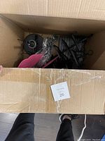 Top-down view inside a shipping box containing parts and pieces of black metal jewelry displays and some pink felt earring holders.