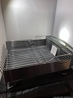 Metal KitchenAid dish rack with wire frame and cutlery basket attached, shown on display.