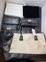 Photo showing four items: black and beige purse, Marc Jacobs deluxe black pouch with original box, Daniel wallet, and Liz Claiborne NY wallet.