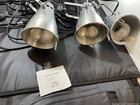 Three aluminum spotlights arranged with their front faces toward the camera, showing the cone shape and front protective grills.