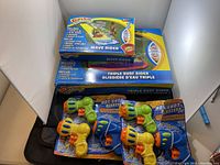 Two boxed Slip & Slide water slides and six Hot Shot Blaster water toys arranged on a surface.